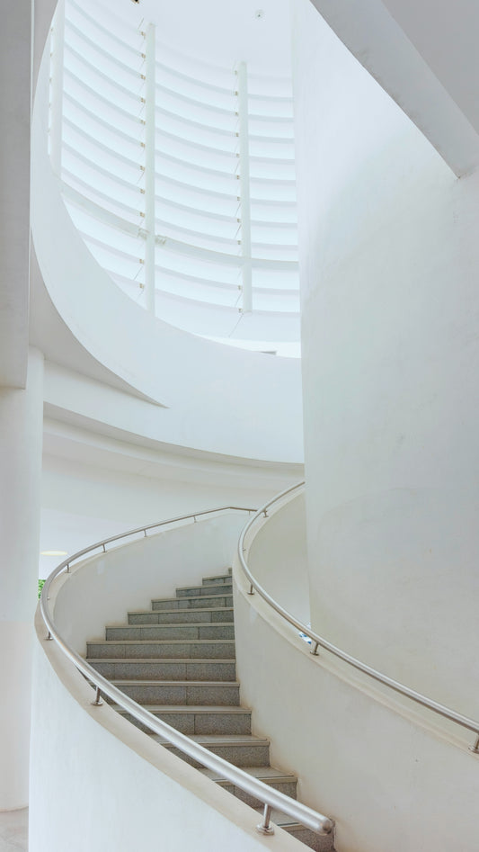 Modern spiral staircase with white walls and metal railing